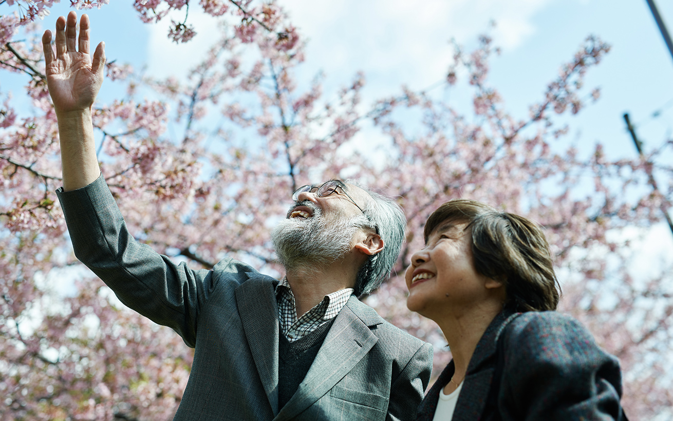 桜の花を見上げるご年配の夫婦